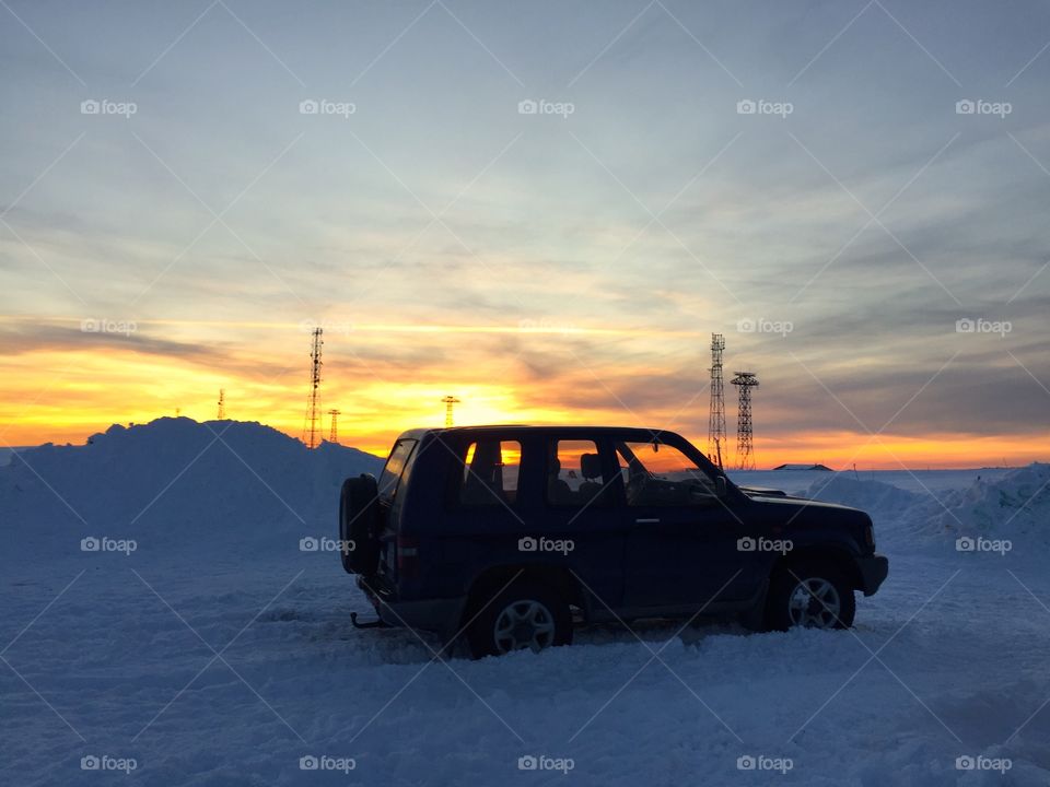 Jeep car on snowy road at sunset