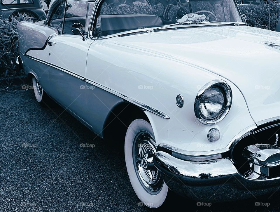 Cool light shot of a blue and cream Oldsmobile 88 taken sideway showing the side and part of the front at Cherbourg car show
