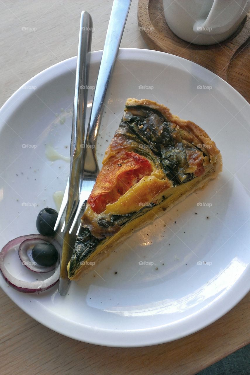 A slice of vegetable tart. A slice of vegetable tart with spinach and tomatoes