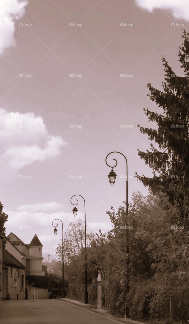 Sepia shot of a street in Maintenon with vintage cast iron lamp posts and lanterns