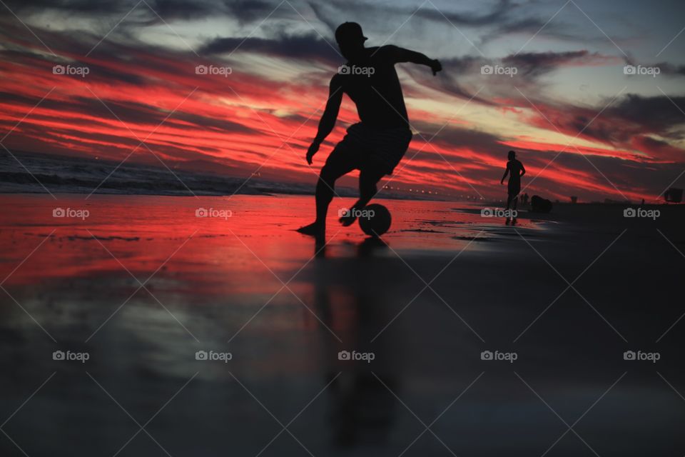 Silhouette of man playing football during sunset