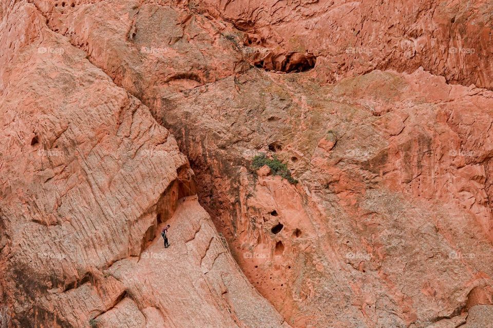 A climber descends down a massive red rock wall