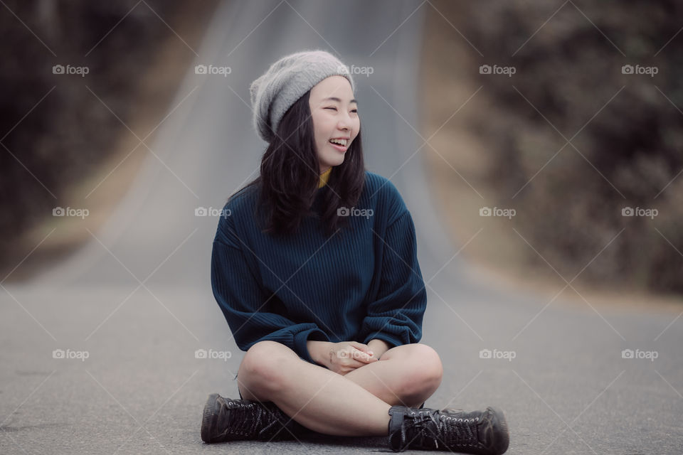 Asian girl smiling and sitting on the road 