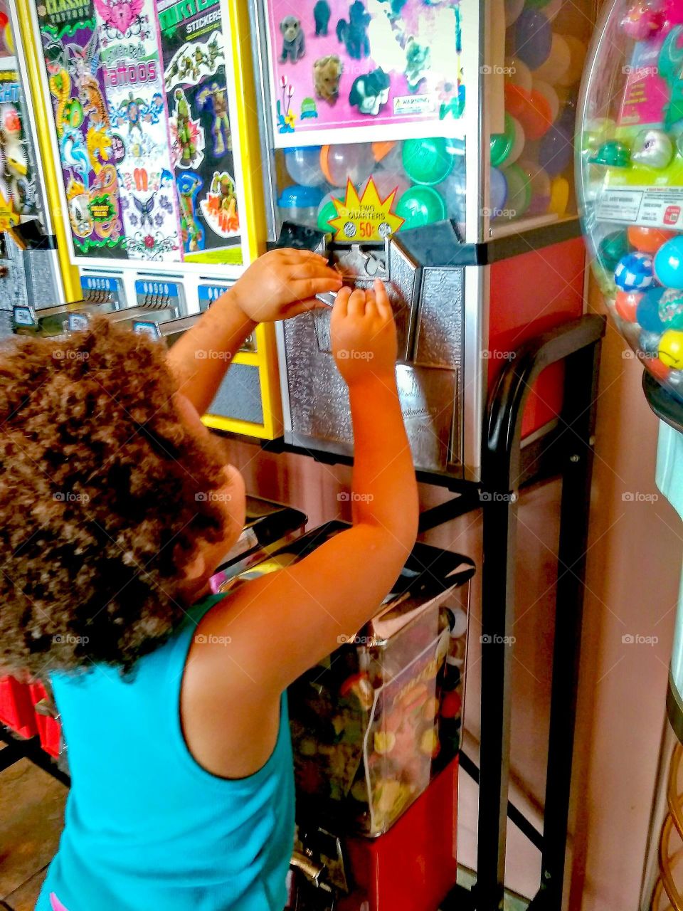 Little girl getting prize out of a Gumball Machine.
