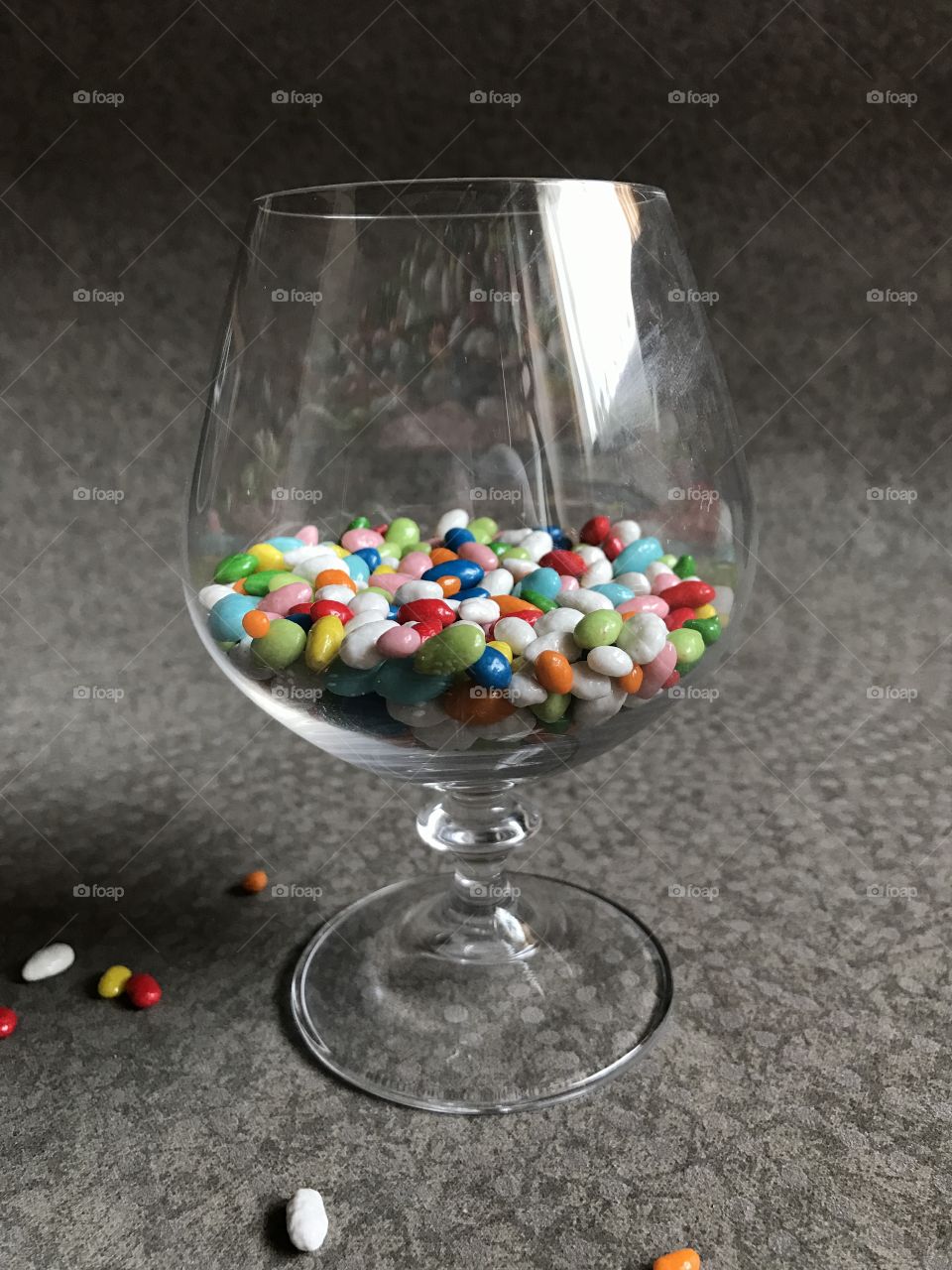 Glass with multicolor candies isolated on grey  