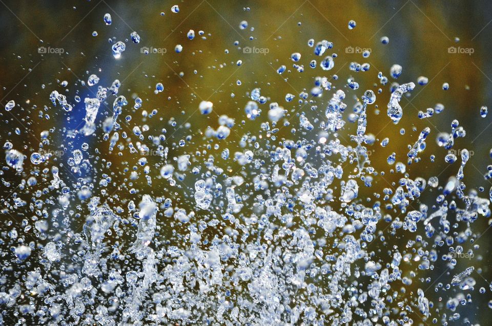 water in motion - water drops from fountain on the colorful background