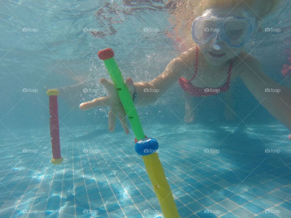 Little girl of four years old diving under water to get her toys in a swimming pool at Alcudia Pins in Alcudia on Majorca.