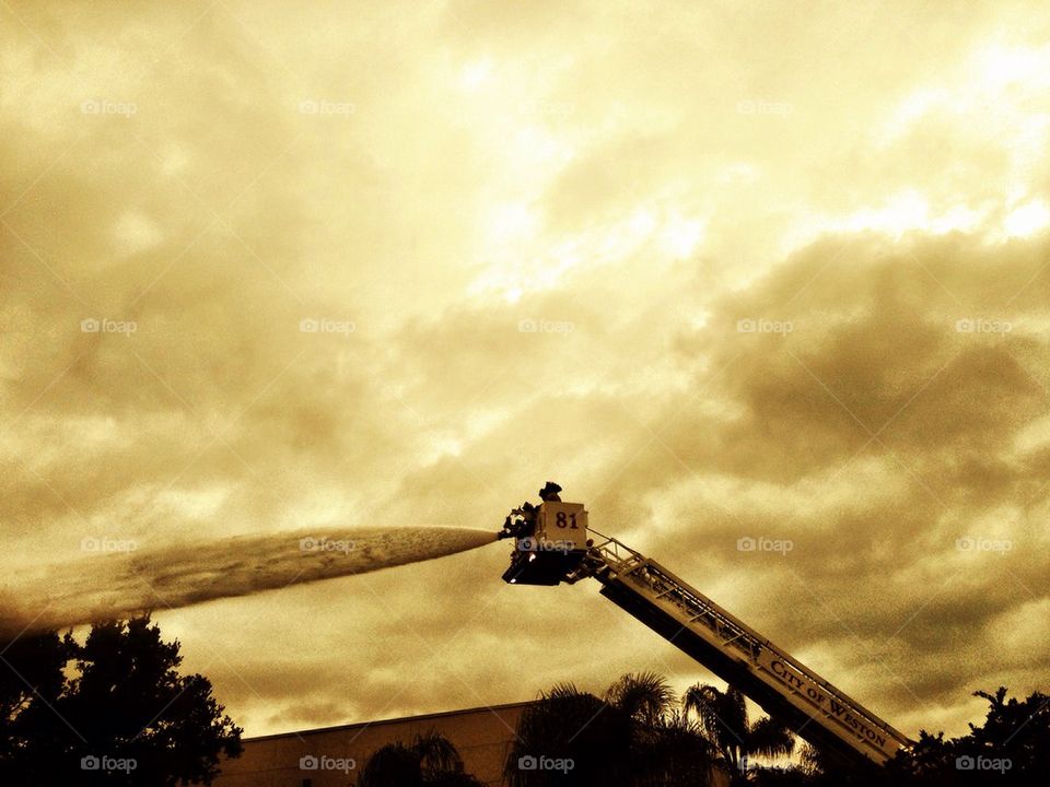 Firemen on a ladder using hose