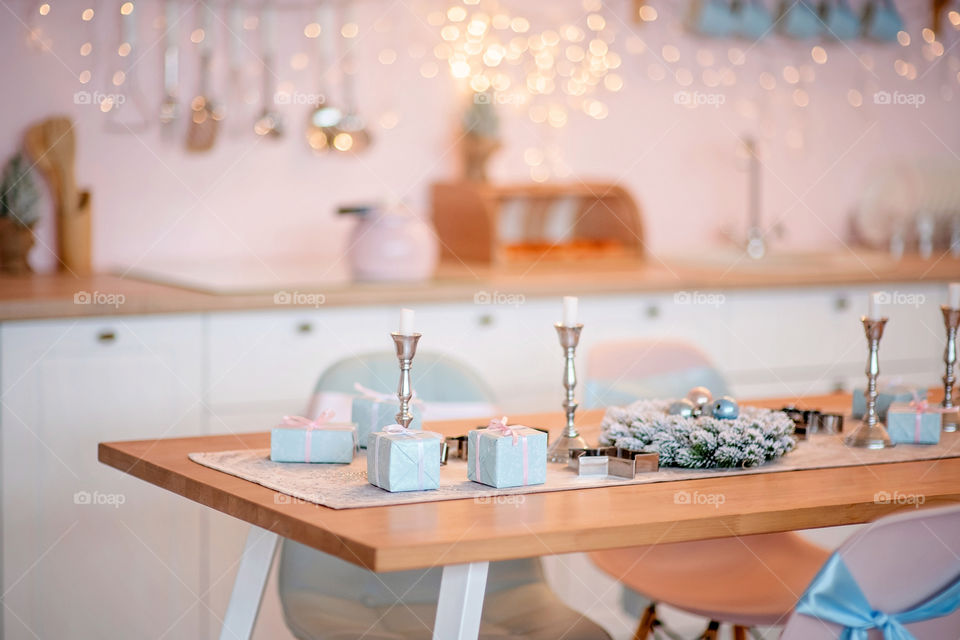 Festive winter cozy kitchen interior with garlands, decorations and gifts.  Christmas dinner at the decorated table.