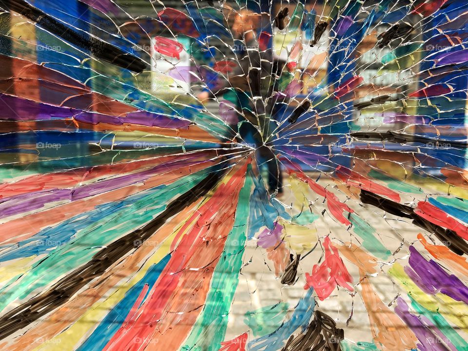 Photo taken from inside a hairdressers of a broken glass window .. staff had coloured it in ... a shopper walks past ... looks much nicer until it gets fixed ...