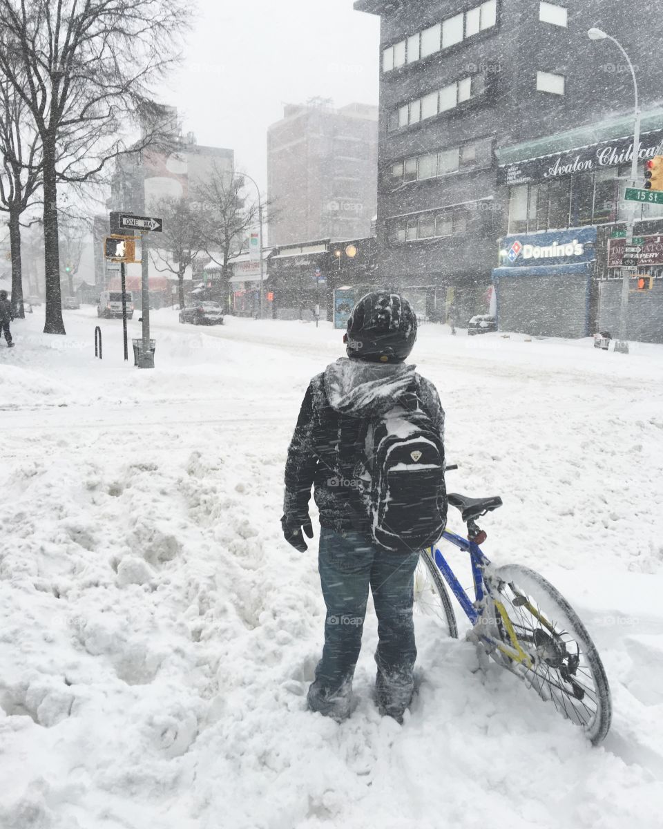 Boy pushing his bicycle through snow drifts in Blizzard Jonas inPark Slope, Brooklyn, New York. 