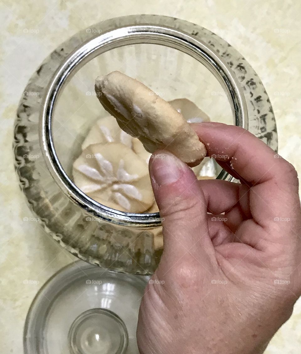 Person hand taking a cookie from a cookie jar