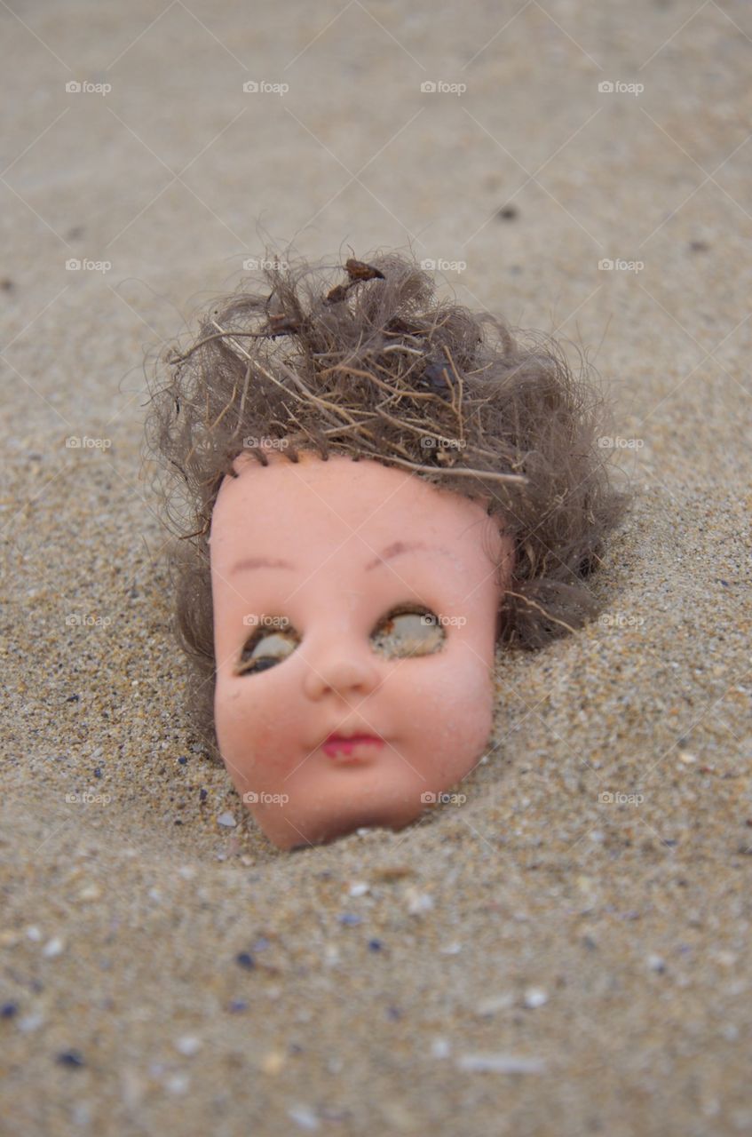 Broken Doll head on the sand