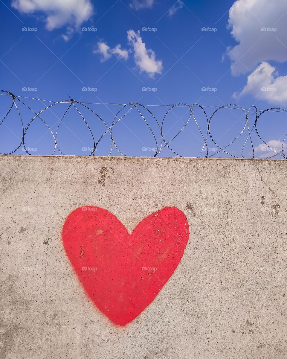 red heart painted on the wall and barbed wire