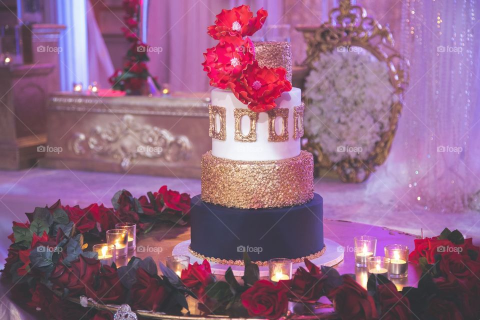 A fancy cake with massive pink flowers and decorated in gold