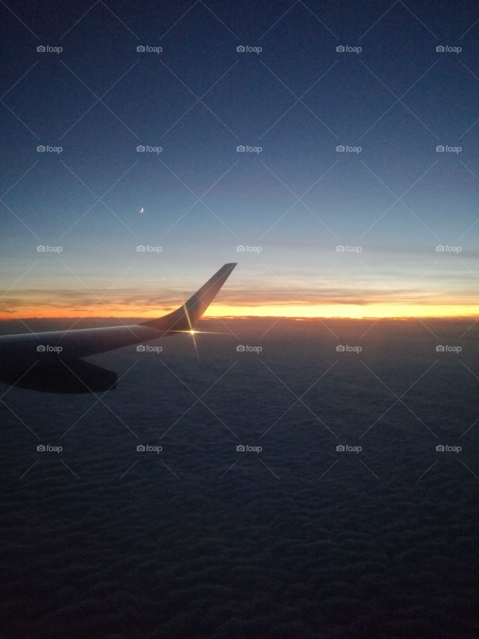 Flying: the moon and the sunset over clouds