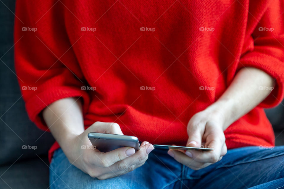 Shopping online on mobile phone using credit card, hands in frame