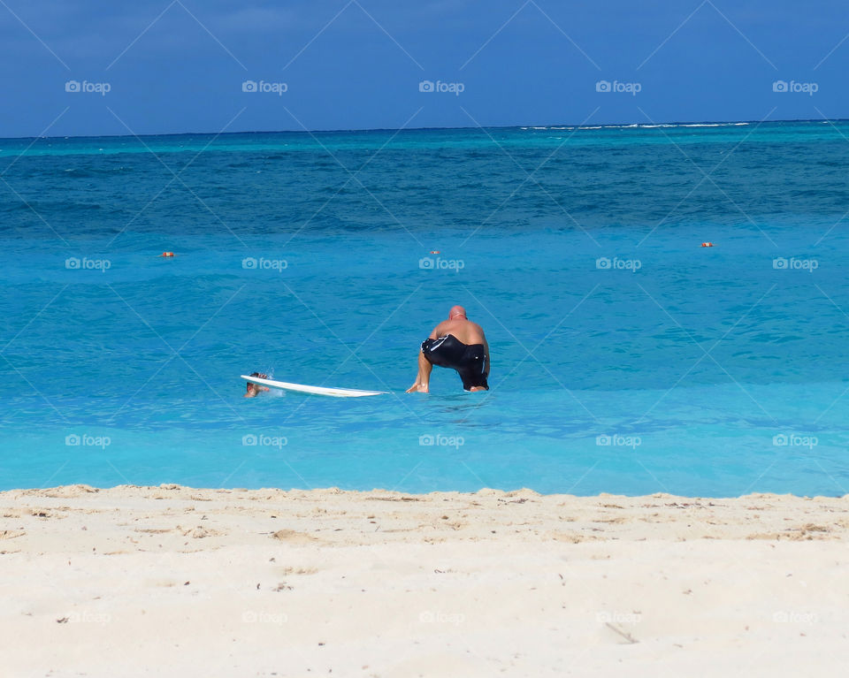 A surfer in the Turks and Caicos Islands trying to learn how to stand up on his surfboard 