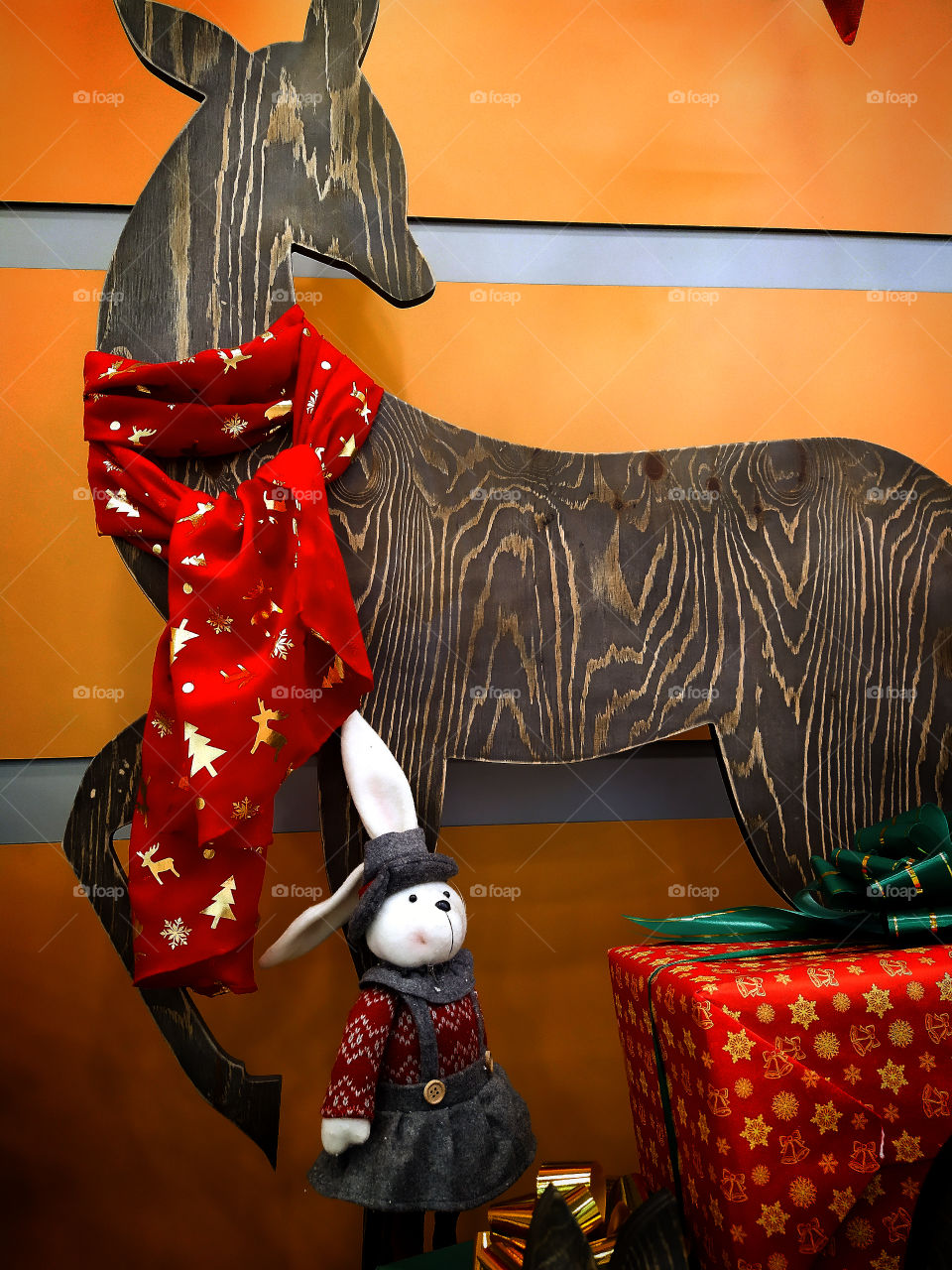 Plush toy rabbit on the background of a wooden deer and boxes for gifts