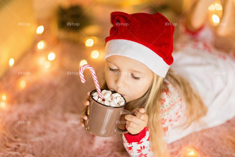 Little girl drinking hot cocoa with marshmallow 