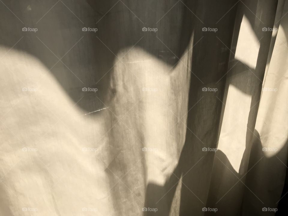 white linen curtain sheet at window with sun light shines on it making beautiful light and shadow