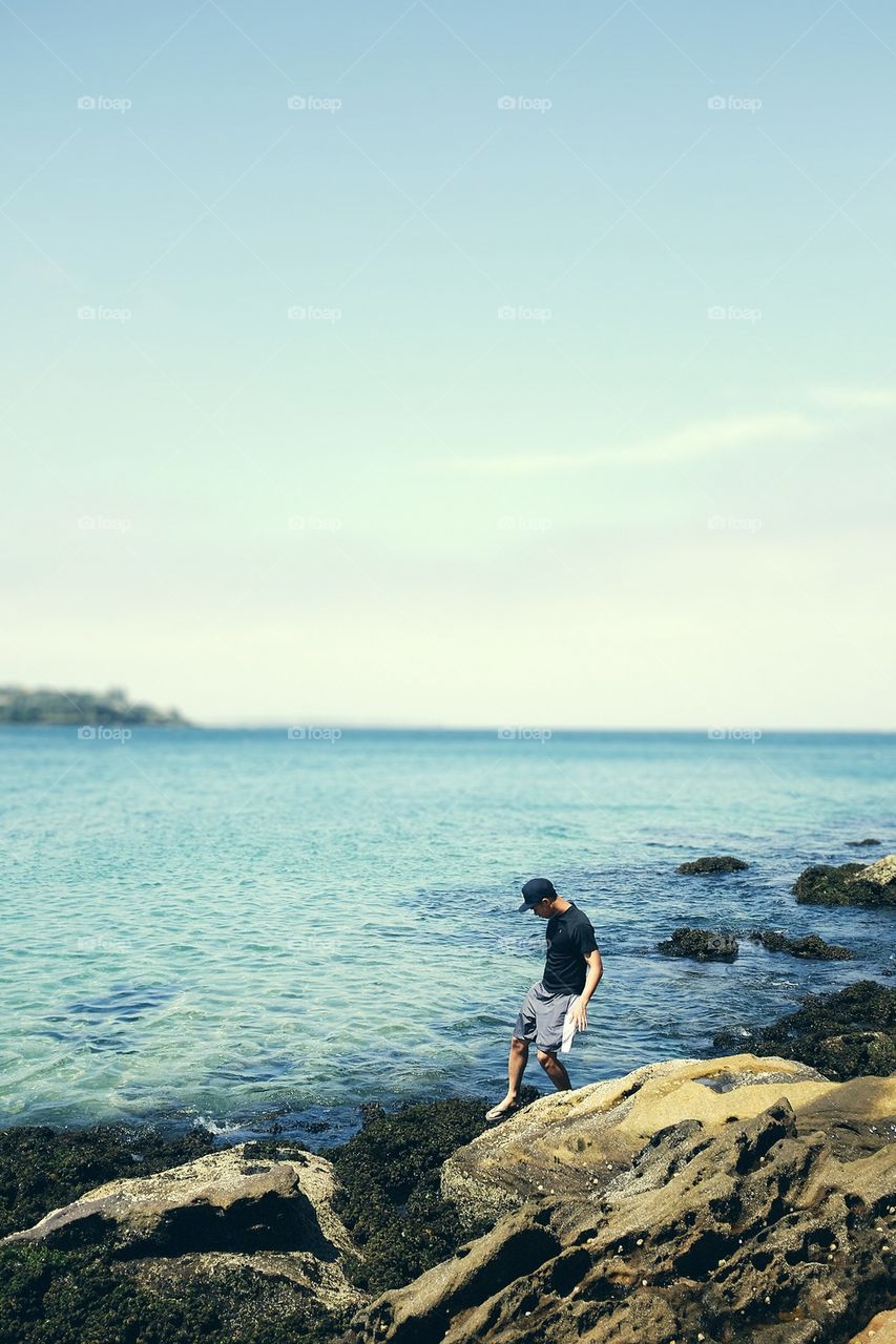 Man sliding down rocks at the ocean's edge
