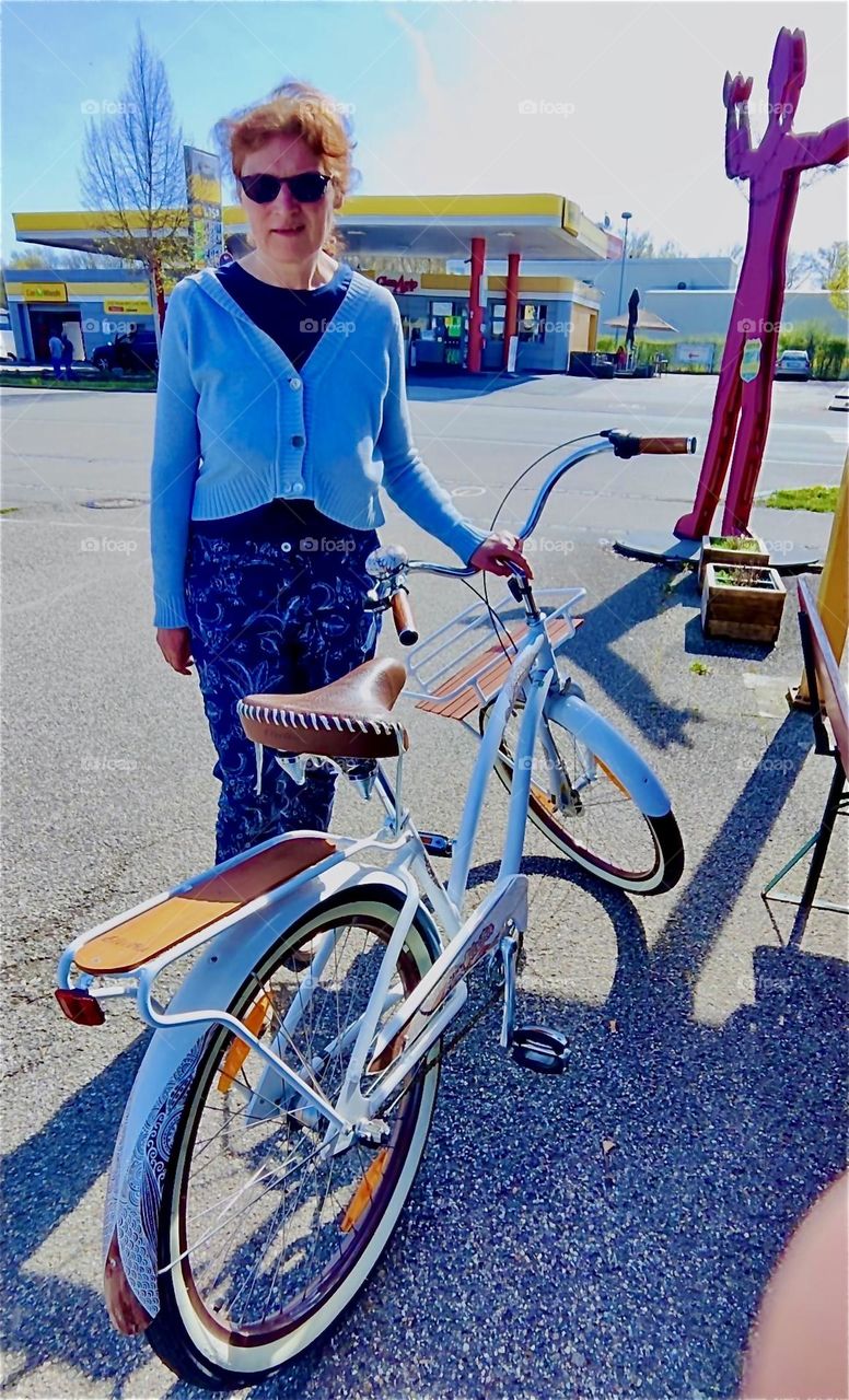 The young lady is apparently happy with her purchase and looks forward to riding her new bicycle on the country roads of rural “Bavaria”, Germany. 2024. Hypnotic Productions