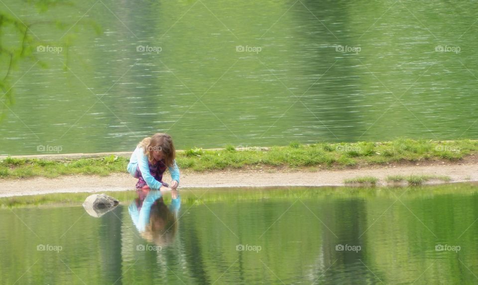 Girl in blue top playing next to water on hot summer day
