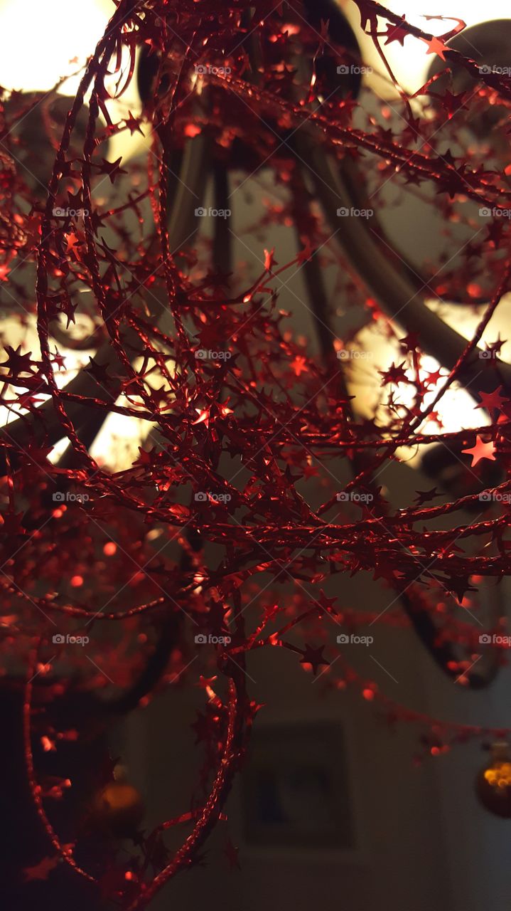 red sparkly decorations hanging off of a chandelier while lit