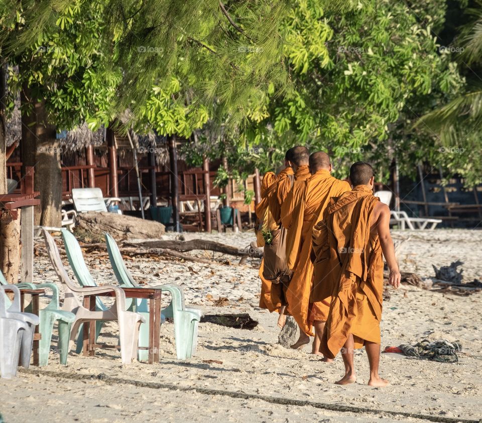 Monks walk along the beautiful beach in the morning