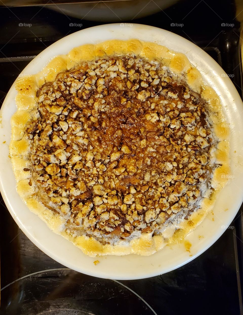 sweet potato casserole with pecan and marshmallow topping in a round white dish bowl