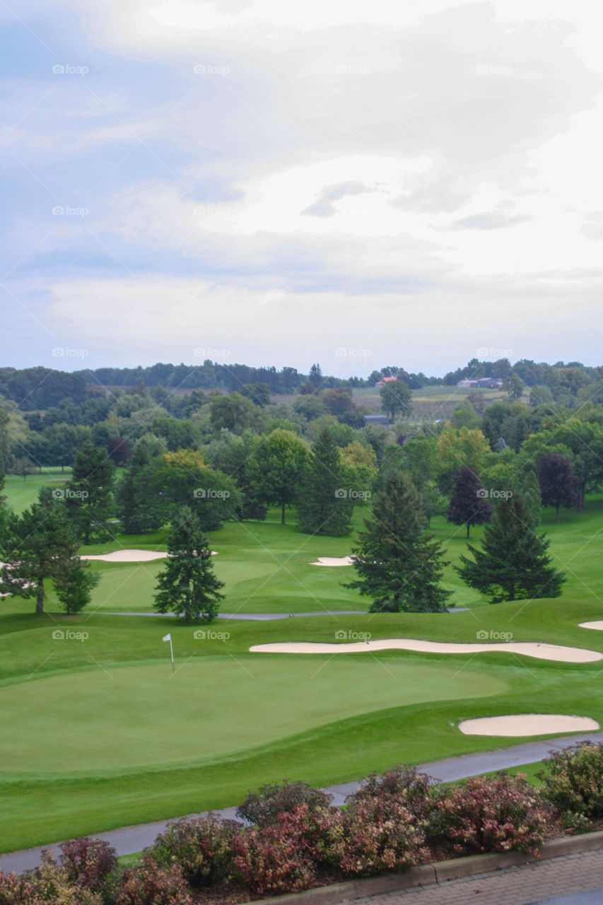 A view of a golf course and forest behind on top of an escarpment 