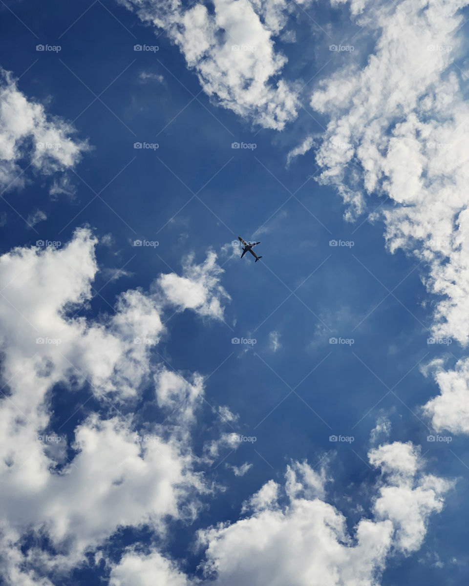 Airplane in the center of the sky or in between the clouds. Beautiful summertime. 