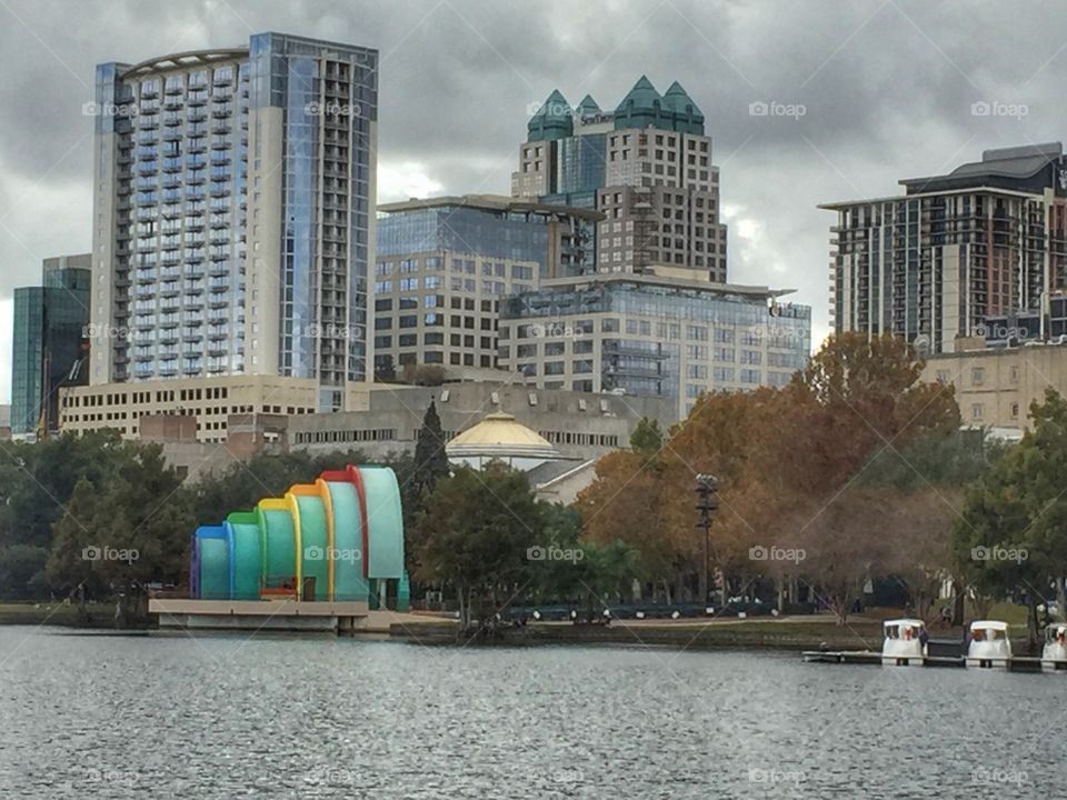 Downtown Orlando skyline against a grey sky with a colorful bandshell on Lake Eola.