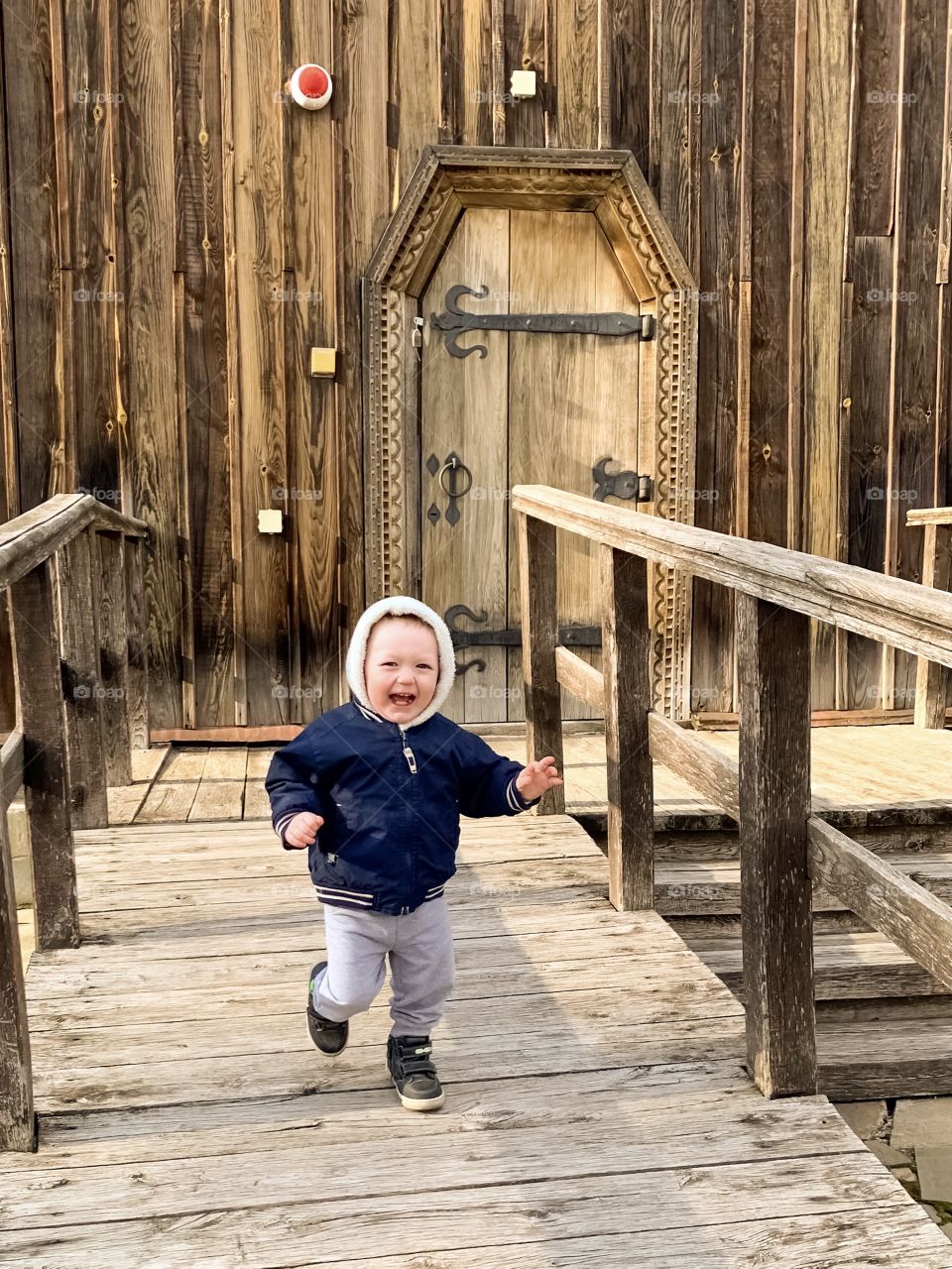 little boy laughs and runs along the ramp of an old wooden church
