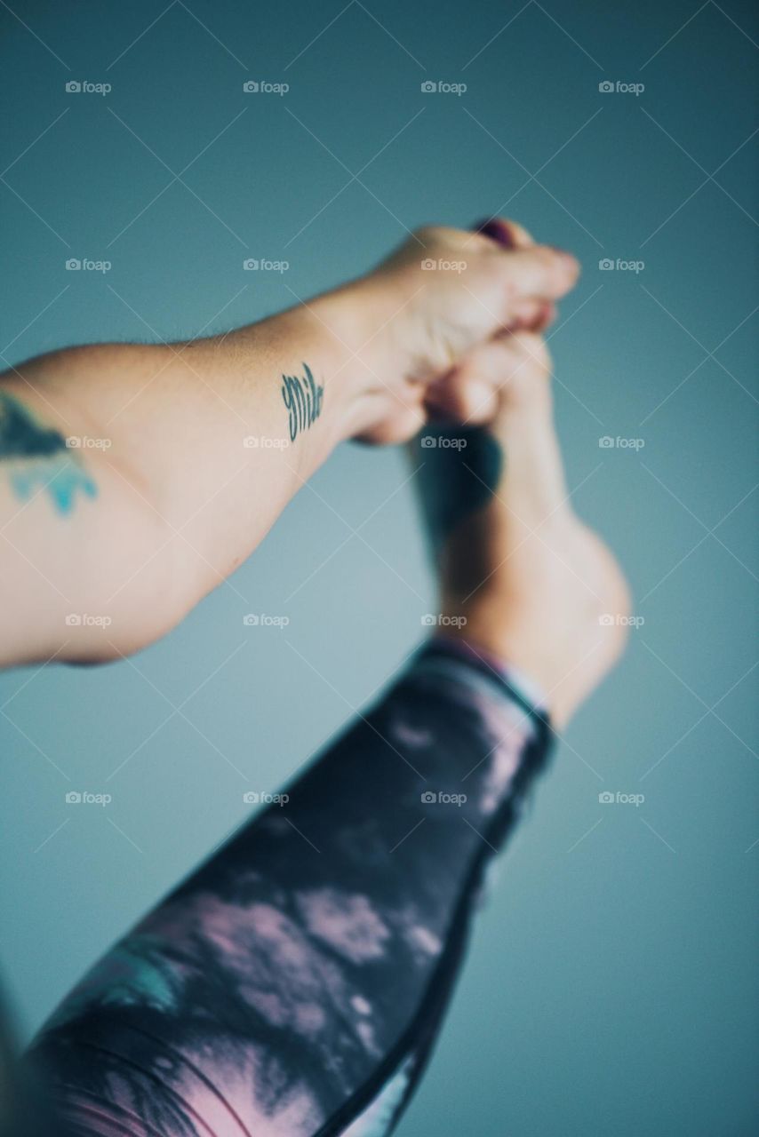 Woman doing a yoga stretch grabbing her foot with her hand 