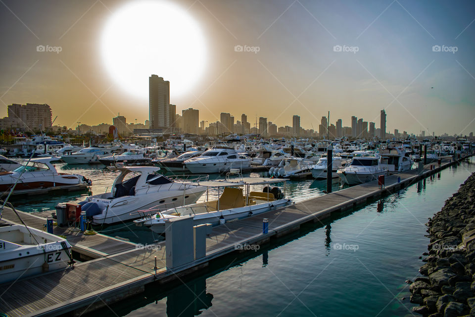 hot sun over the marina with kuwait city skyline in the background