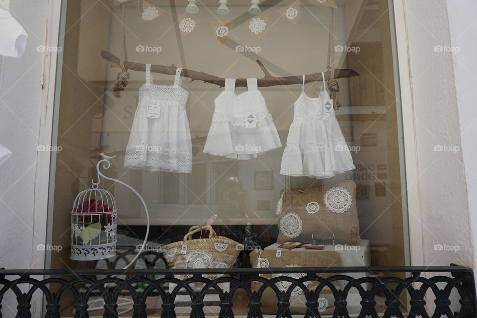 Three beautiful white dresses for sale … cleverly displayed hanging from a tree branch in a shop window … If you look carefully you can see my reflection … taking the photo with a white camera and a white building behind me 😉🤍