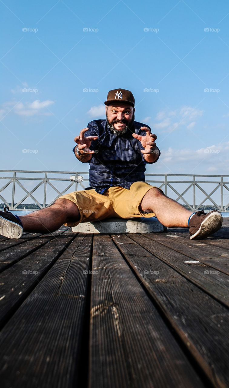 Funny man sitting on pier