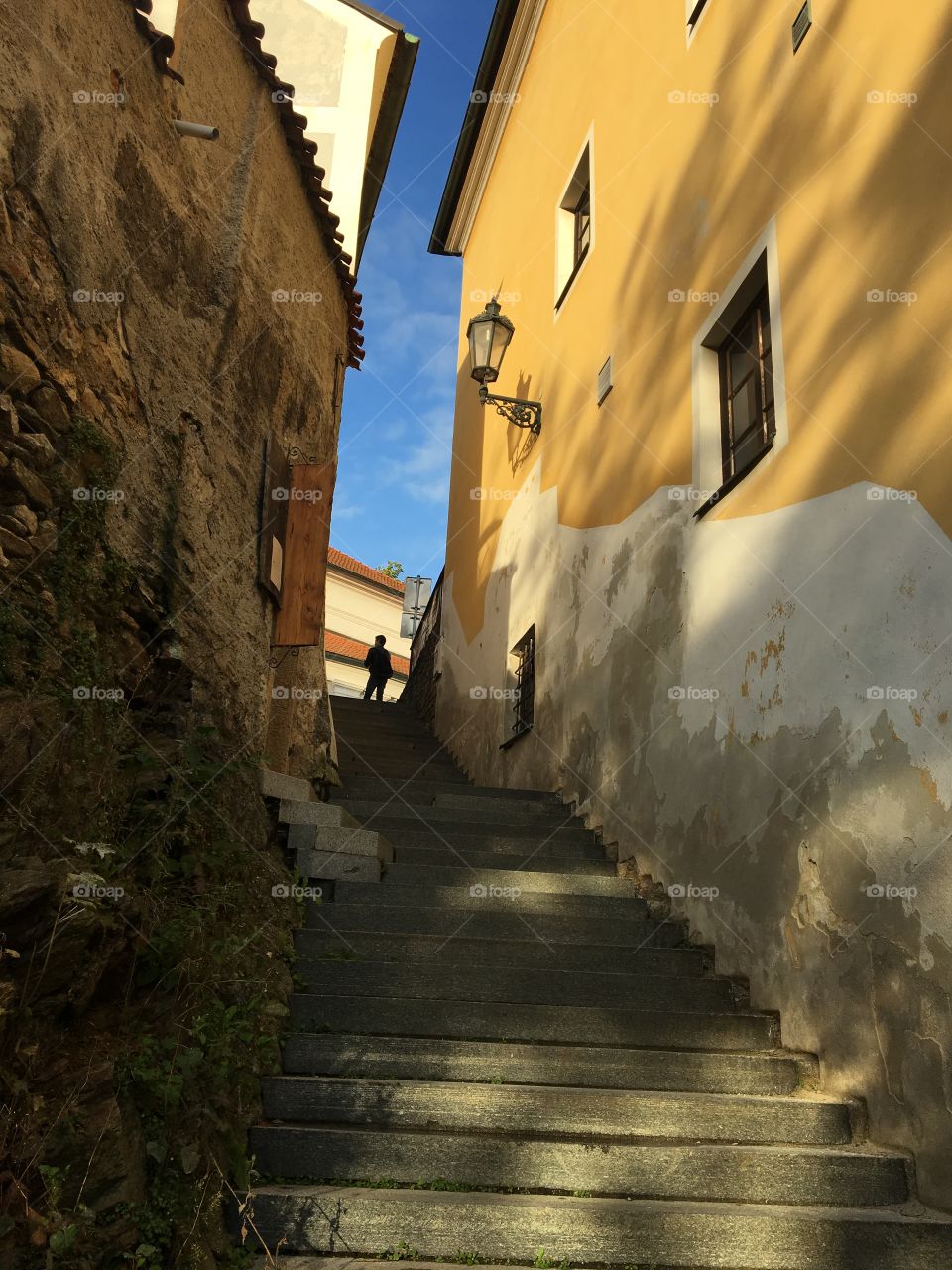 Steep flight of steps in Cesky Krumlov .. beautiful yellow painted house contrasting against the blue sky 