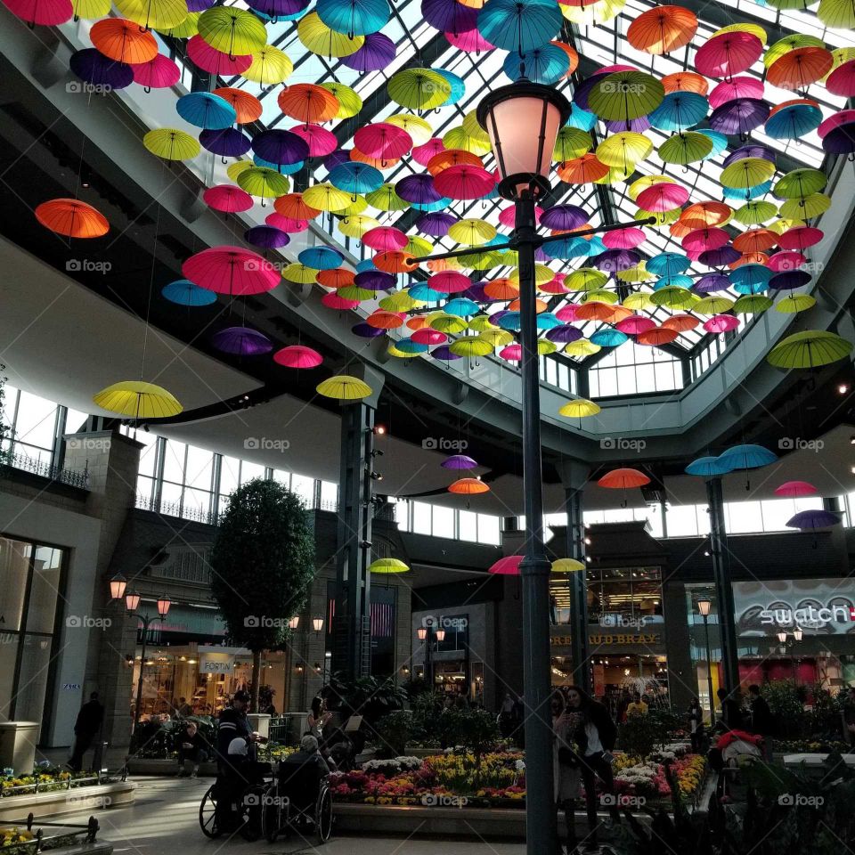 colorful umbrellas creating artistic effect!
daylight streaming through the open roof 
#roof #colours #art #umbrellas #creative #parapluie #public #summertime #fun