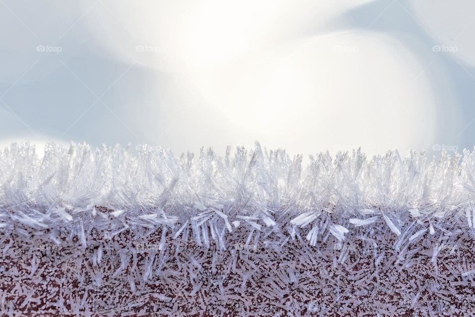 Closeup of frost covering wooden fence on a cold sunny winter day with bokeh in the background 