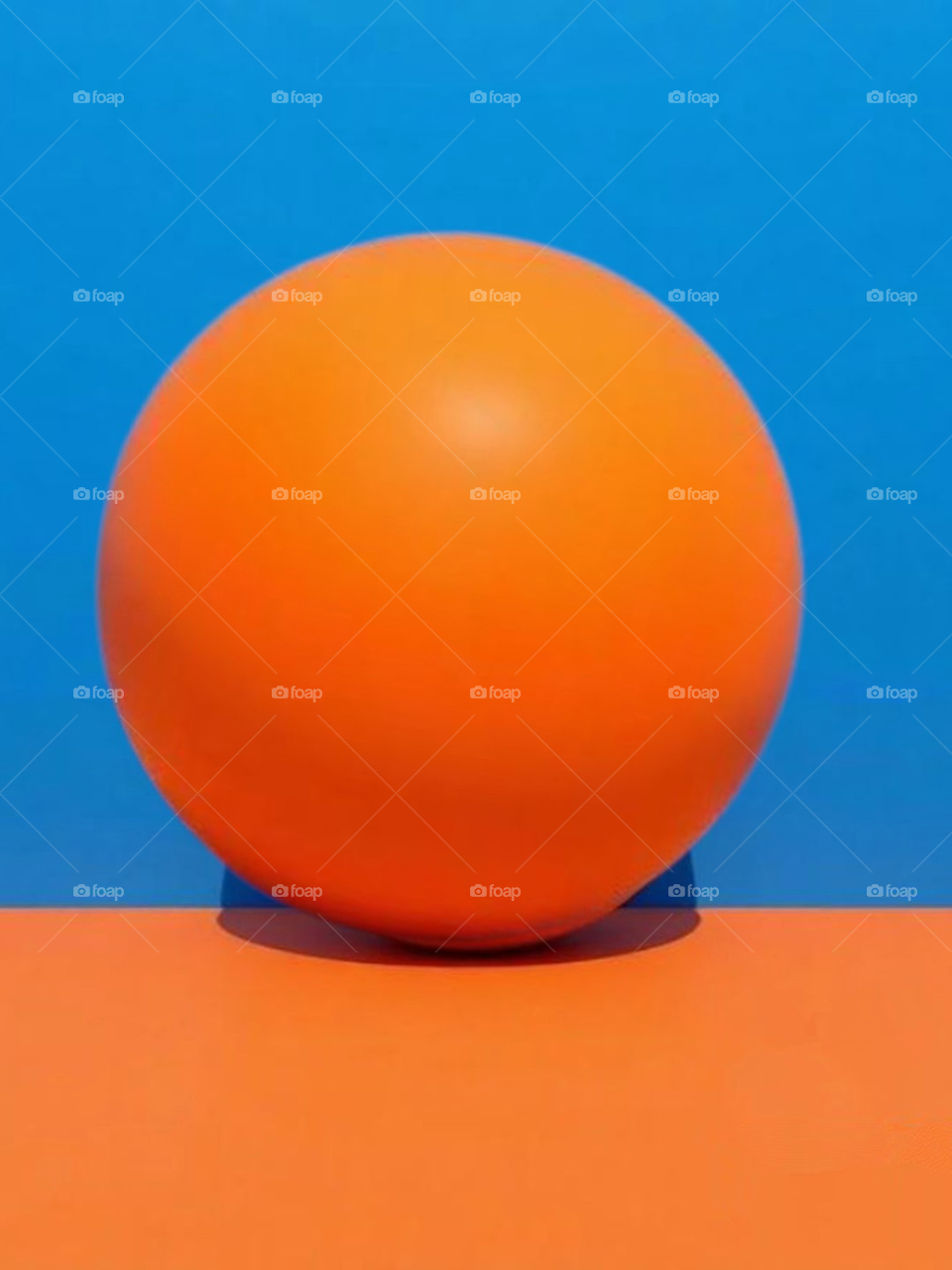 Orange ball in front of a blue wall