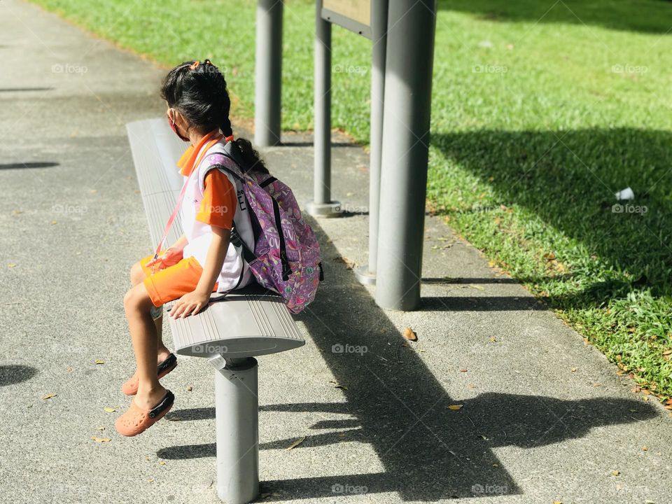 School girl funny shadow on her back while waiting for the bus to go school 