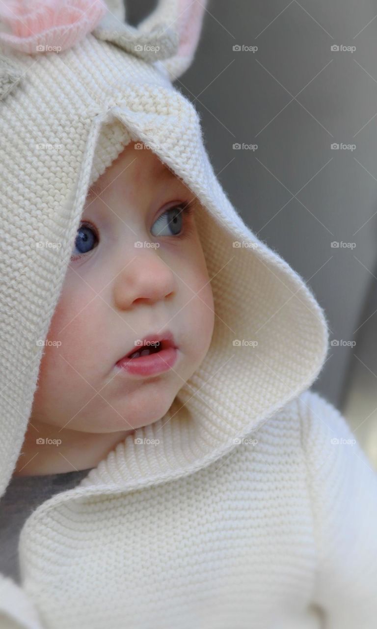 Rosy cheeked toddler girl wears an adorable crème colored sweater outside on a brisk Winter day 