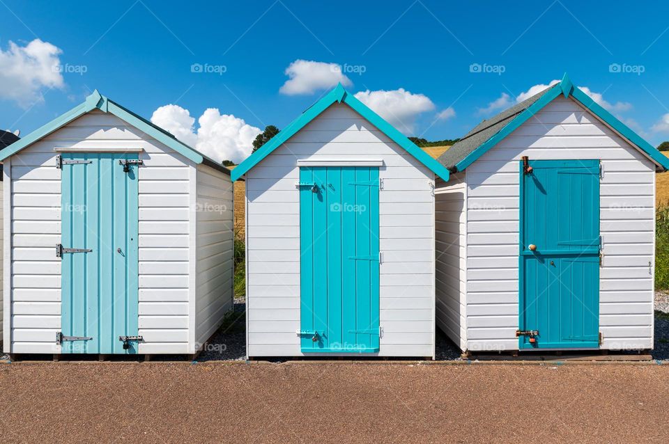 Colorful in white and blue small beach houses. Multicolored beach sheds. Variety of painted beach shacks.