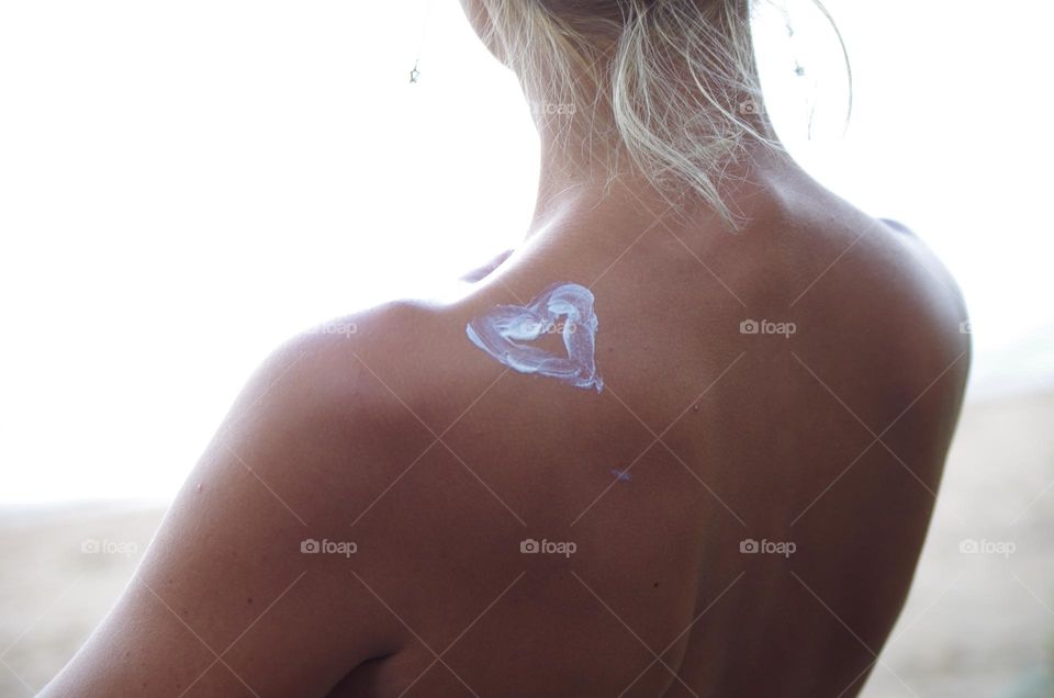 a young woman has a heart painted on her shoulder with cream