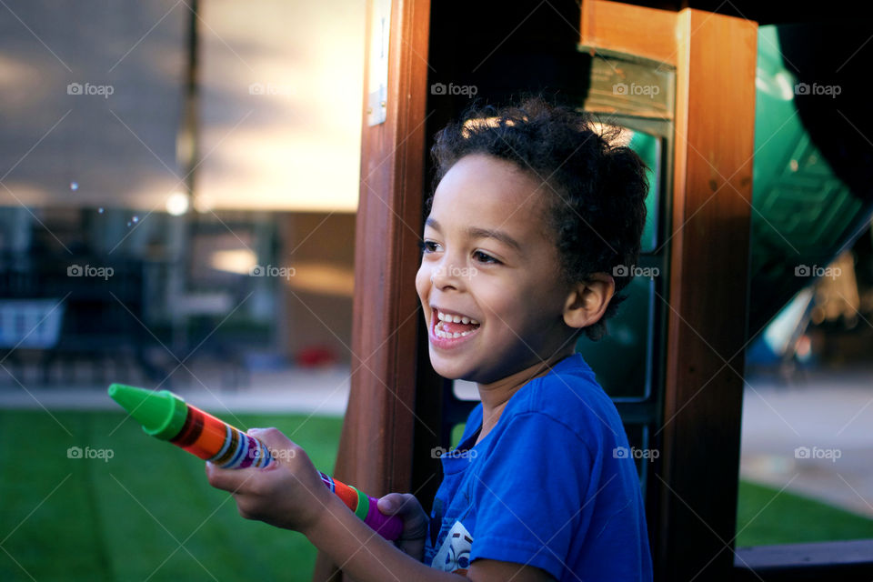 Little boy playing outside with water gun