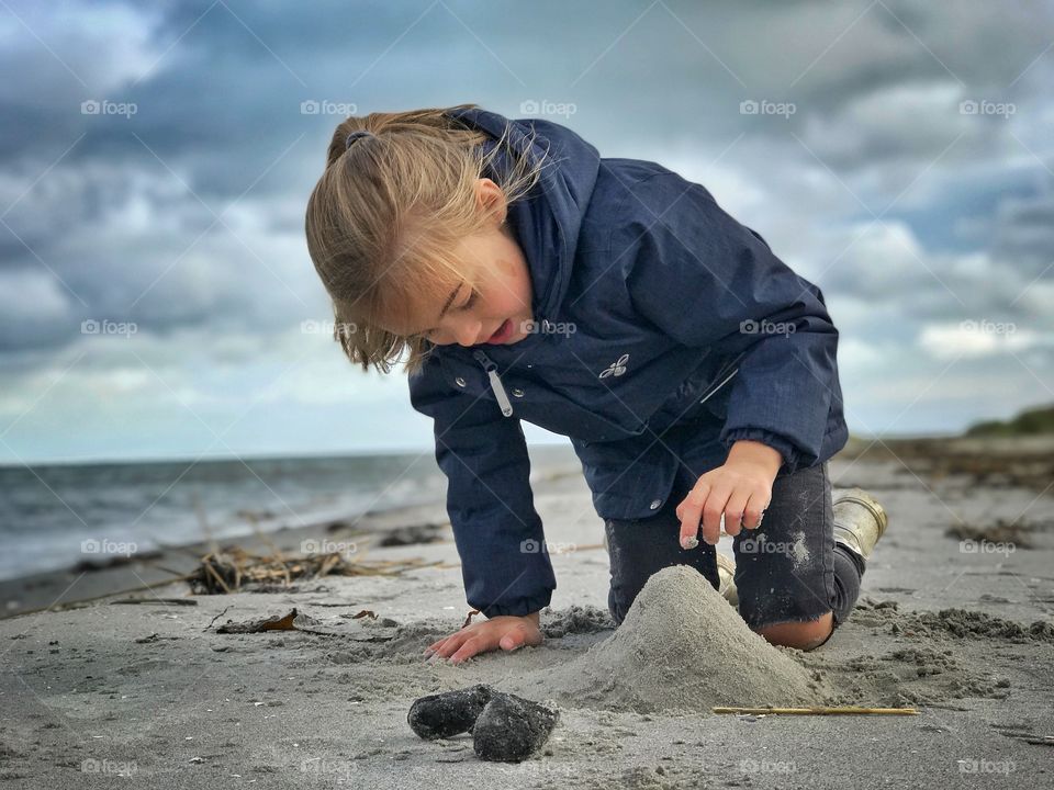 Playing with sand at the beach on a cold day