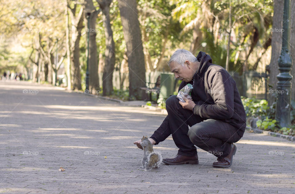 Old man feeding cute squirrel